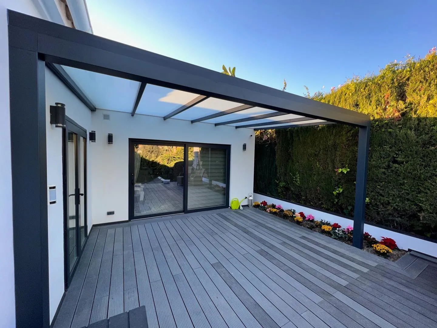 Glass roof over a decked terrace beside a white villa